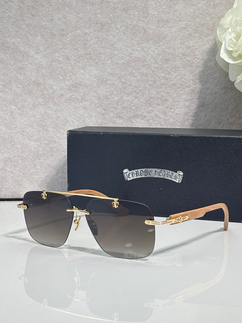 Chrome sunglasses with dark blue lenses, black frame, and light wood-effect temples.
