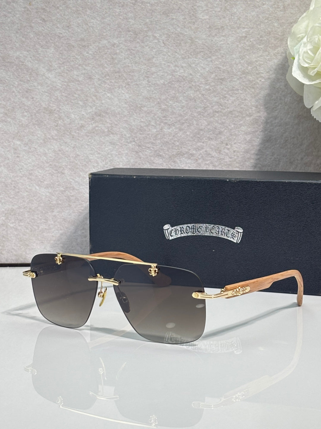 Chrome sunglasses with dark blue lenses, black frame, and light wood-effect temples.