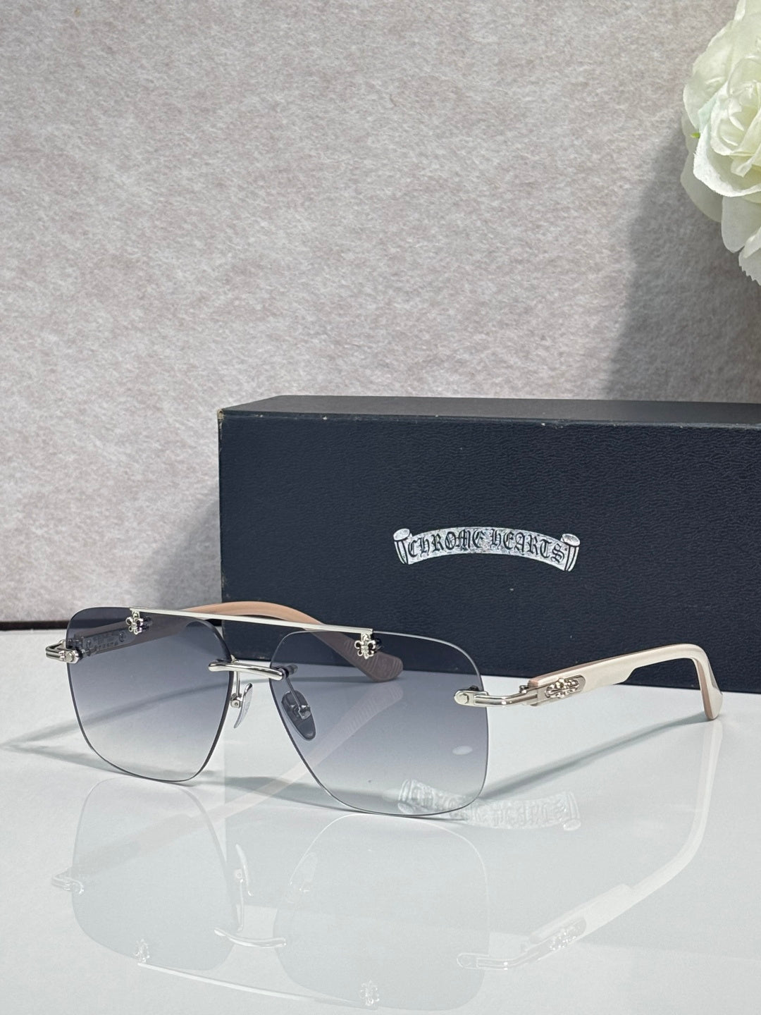 Chrome sunglasses with dark blue lenses and thin metal frame, with gold-tone temple accents.