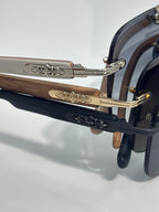 Side view of chrome sunglasses with blue lenses, metal arms, and carved gold-tone trim.