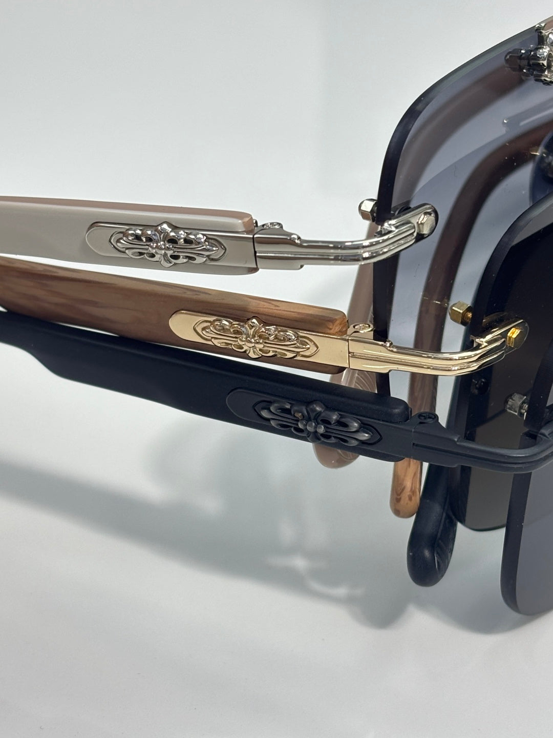 Side view of chrome sunglasses with blue lenses, metal arms, and carved gold-tone trim.