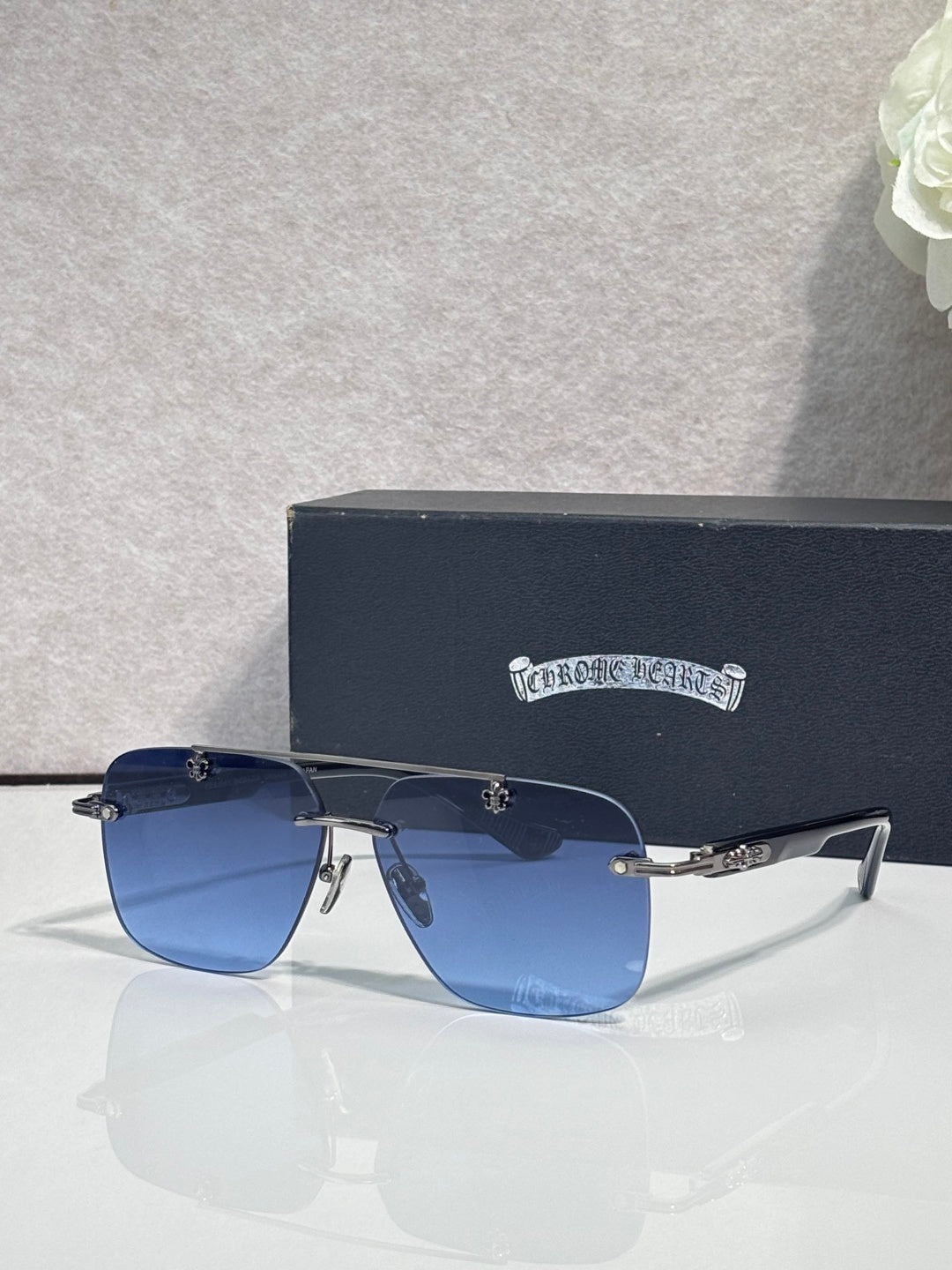 Chrome sunglasses with dark blue lenses, black frame, and gold-tone accents on temples.