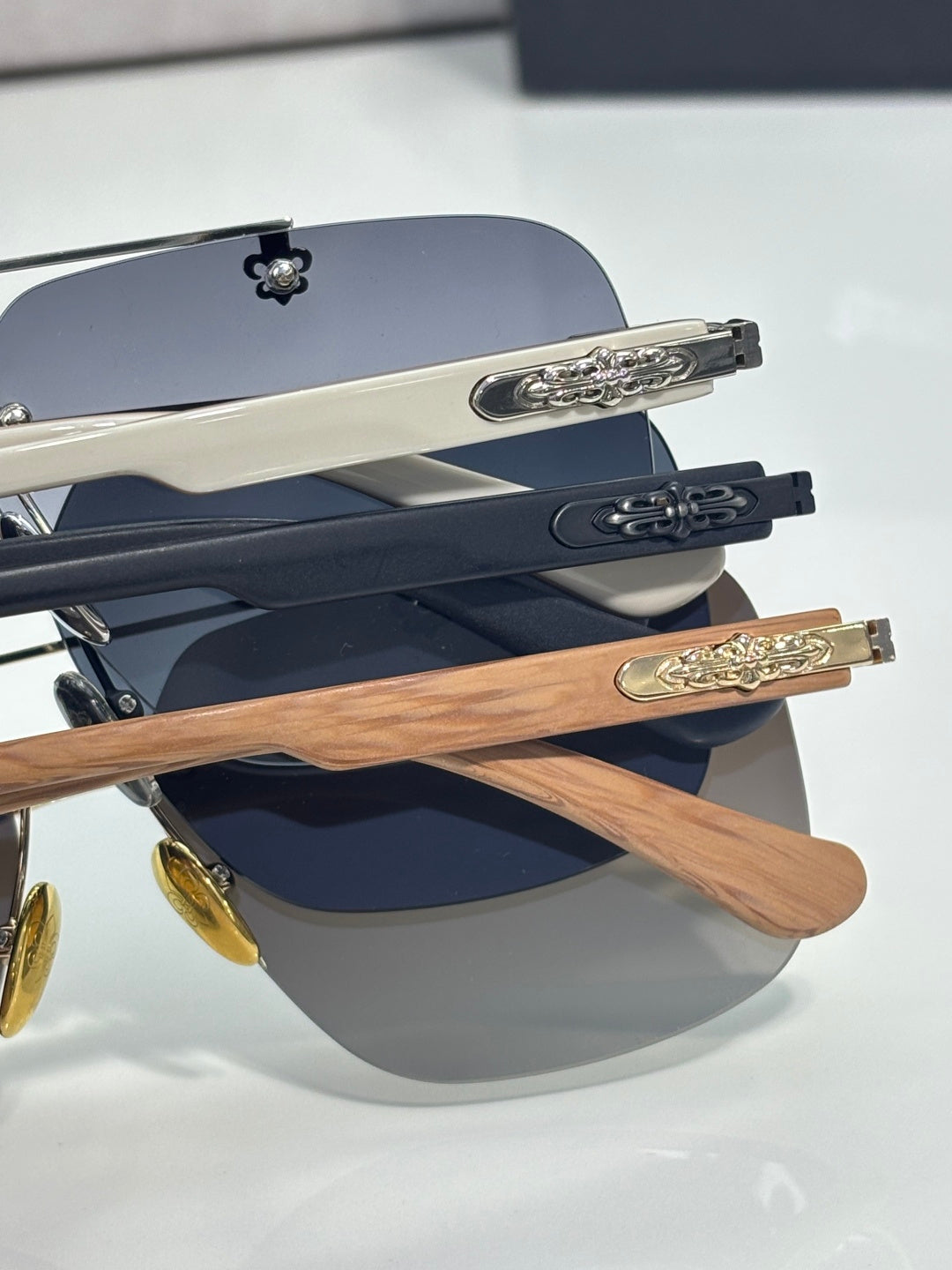 Grouped chrome sunglasses featuring dark blue lenses and wood-effect arms with gold-tone plates.
