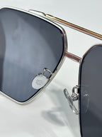 Sunglasses close-up: silver edge frame with dark lenses and decorative bridge detail
