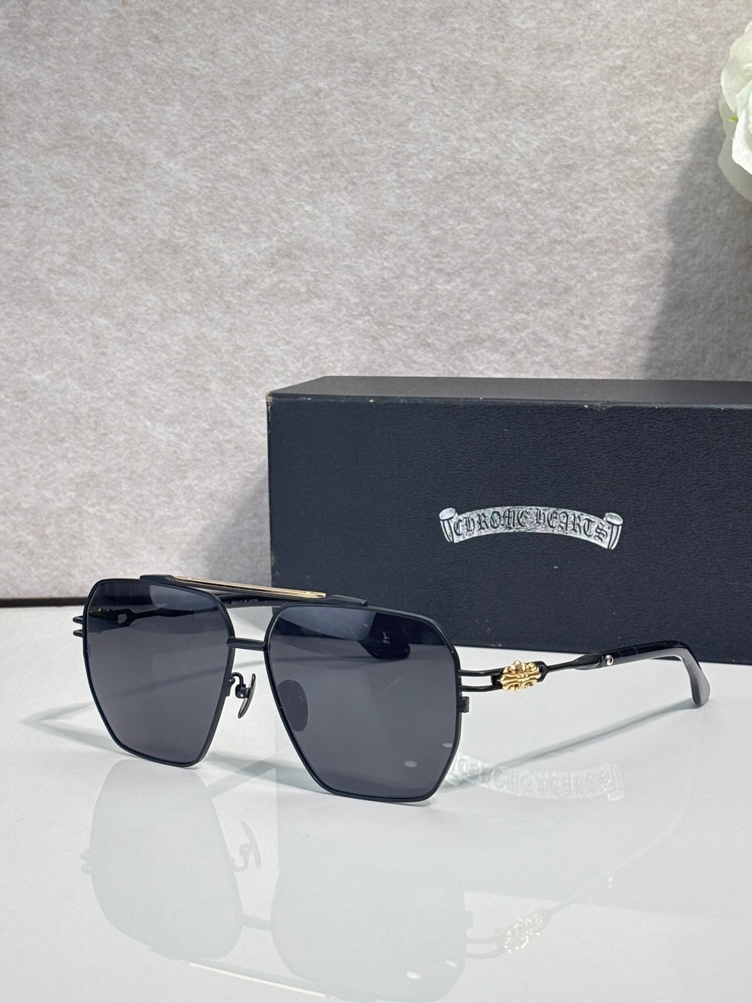 Sunglasses with gold-tone frame and dark tinted lenses, rectangular square shape