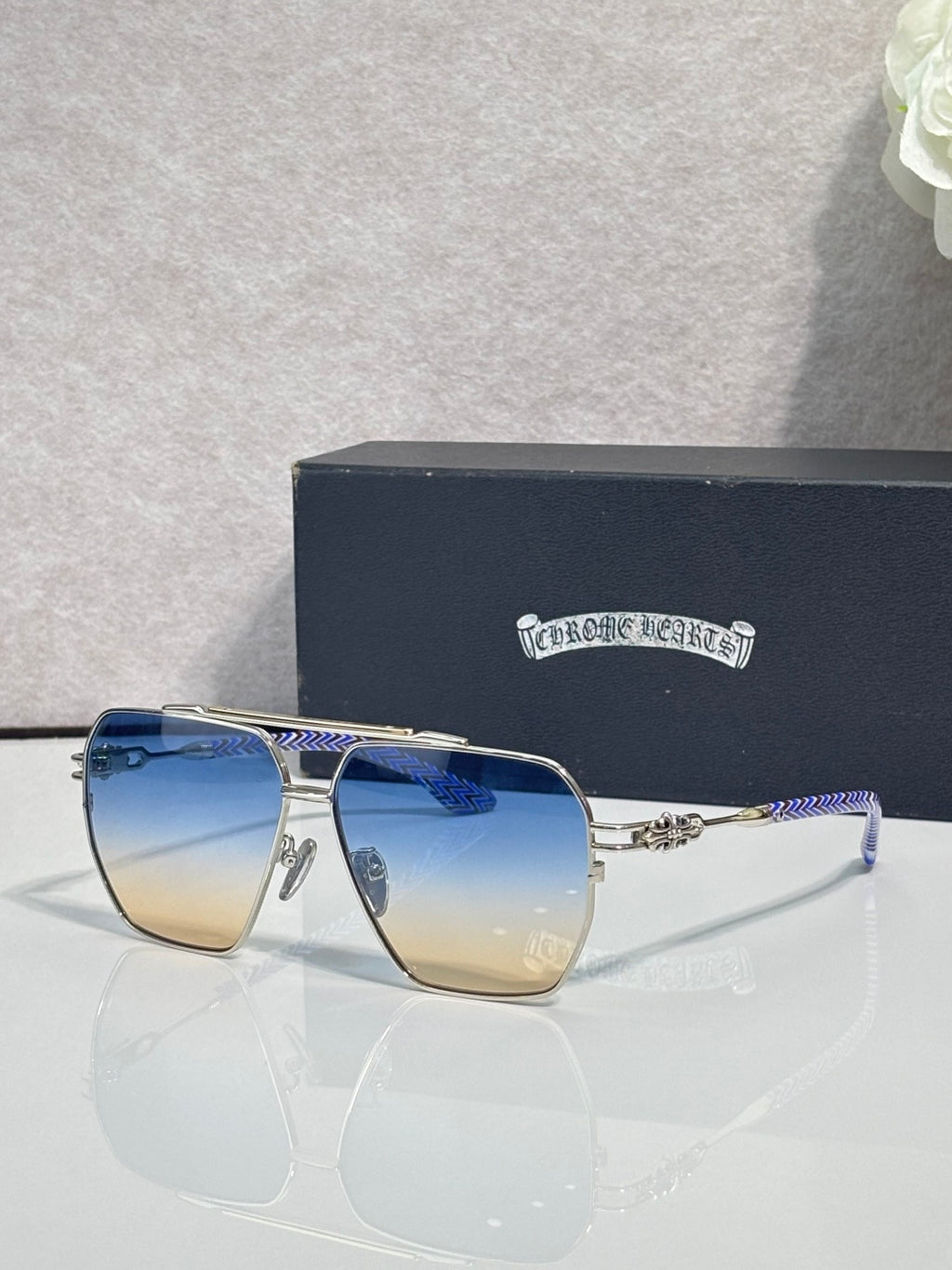 Sunglasses with gold-tone frame and gradient blue lenses, rectangular square shape