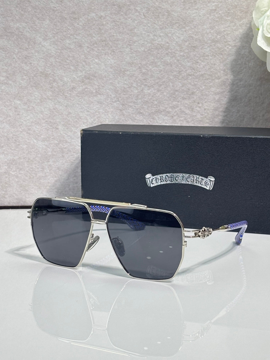 Sunglasses with gold-tone frame and dark blue tinted lenses, rectangular square shape