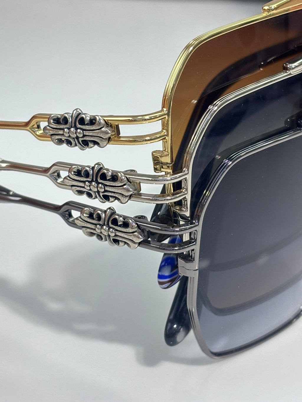 Sunglasses close-up: ornate metal hinge detail on gold-tone frame