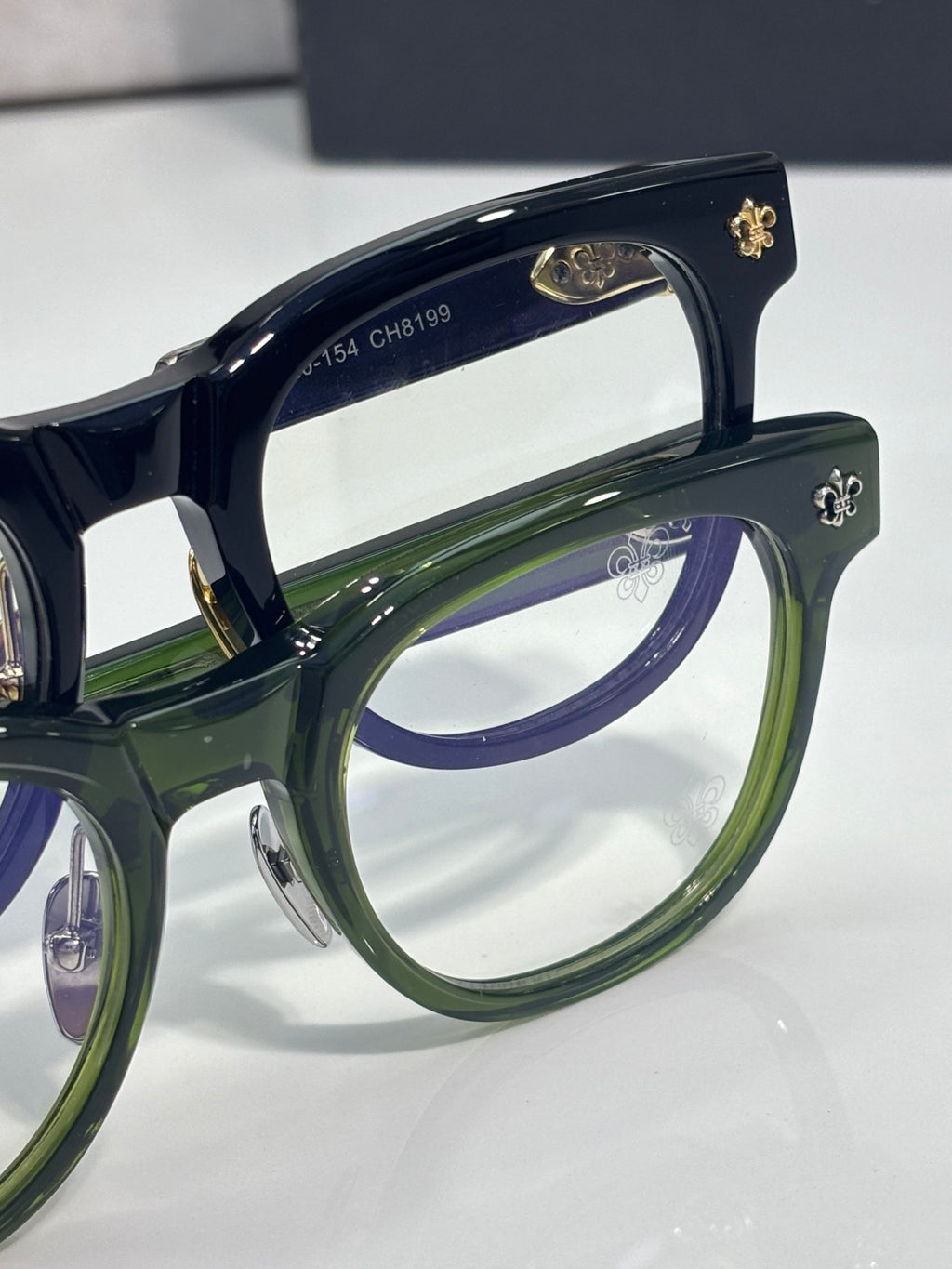 Navy blue glasses with green inner rims and gold decorative frame details