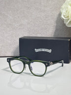 Green full-rim glasses with clear lenses and gold-tone temple accents