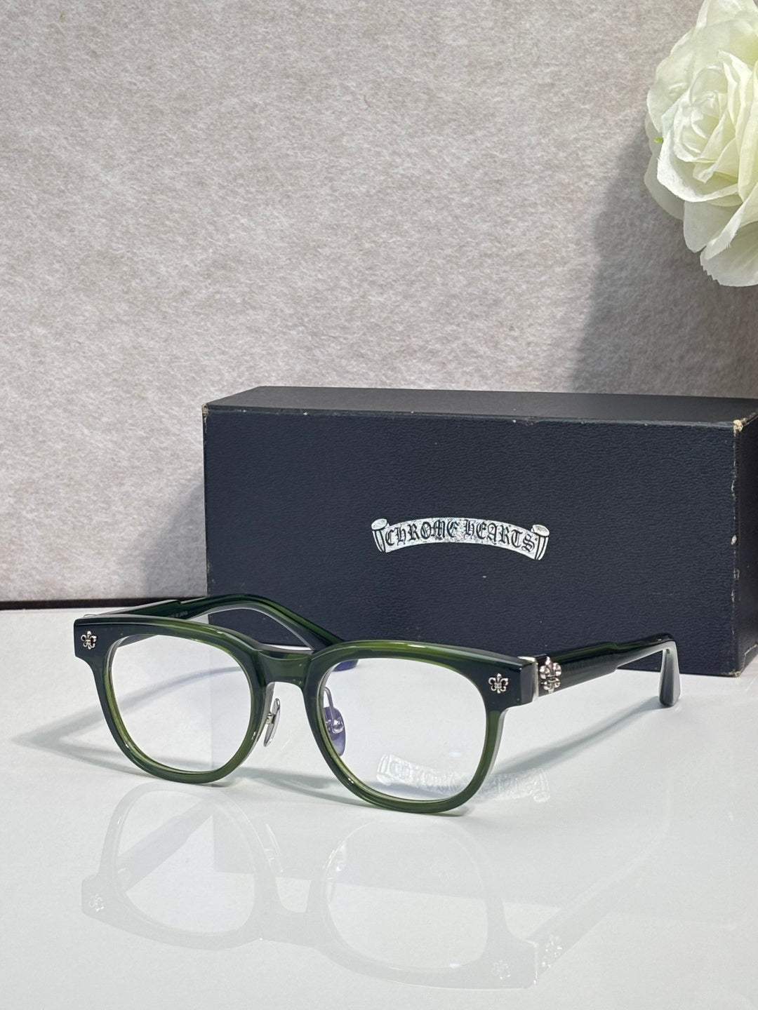 Green full-rim glasses with clear lenses and gold-tone temple accents