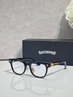 Black full-rim glasses with clear lenses and gold-tone decorative temple tips