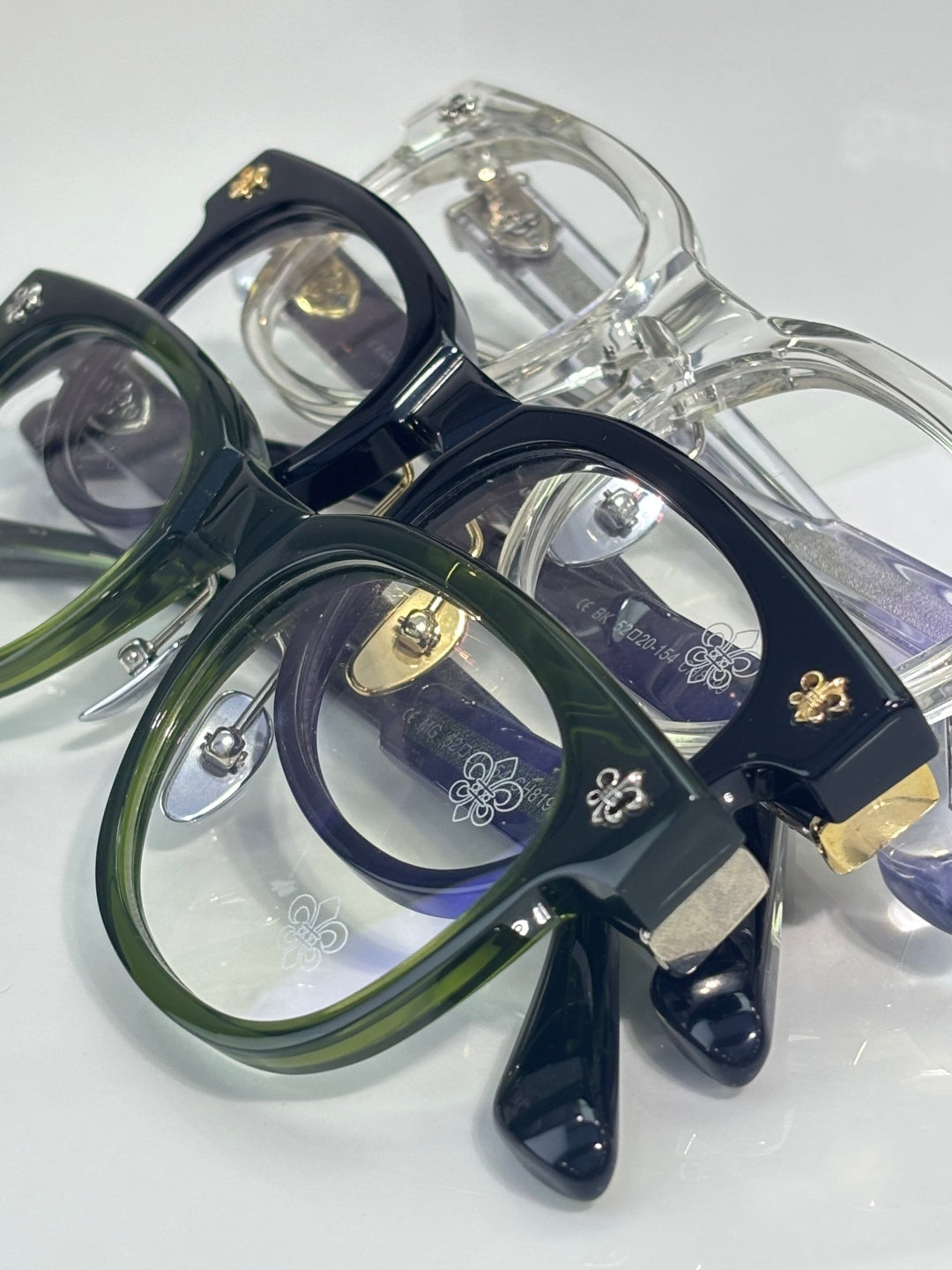 Set of full-rim glasses in navy, green, and clear tones with ornate gold accents