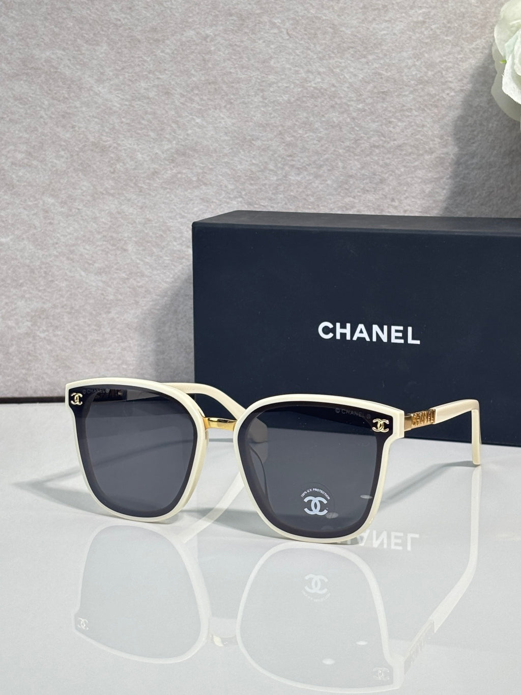 Chanel sunglasses with cream frames, dark lenses, and gold logo temple details