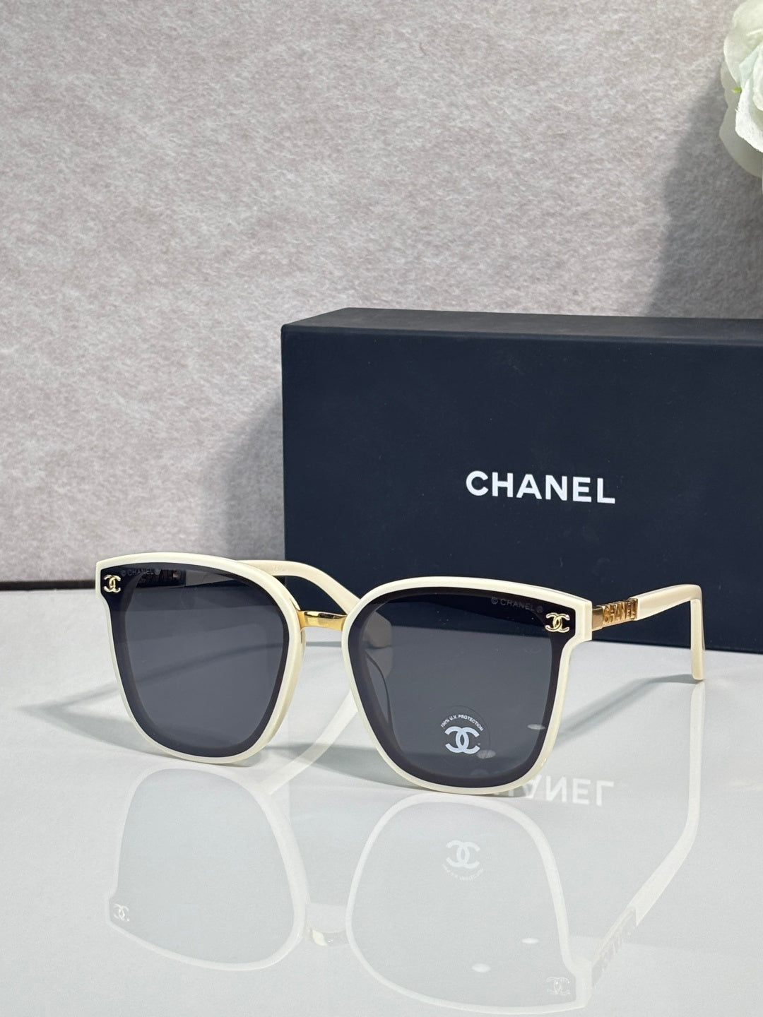 Chanel sunglasses with cream frames, dark lenses, and gold logo temple details