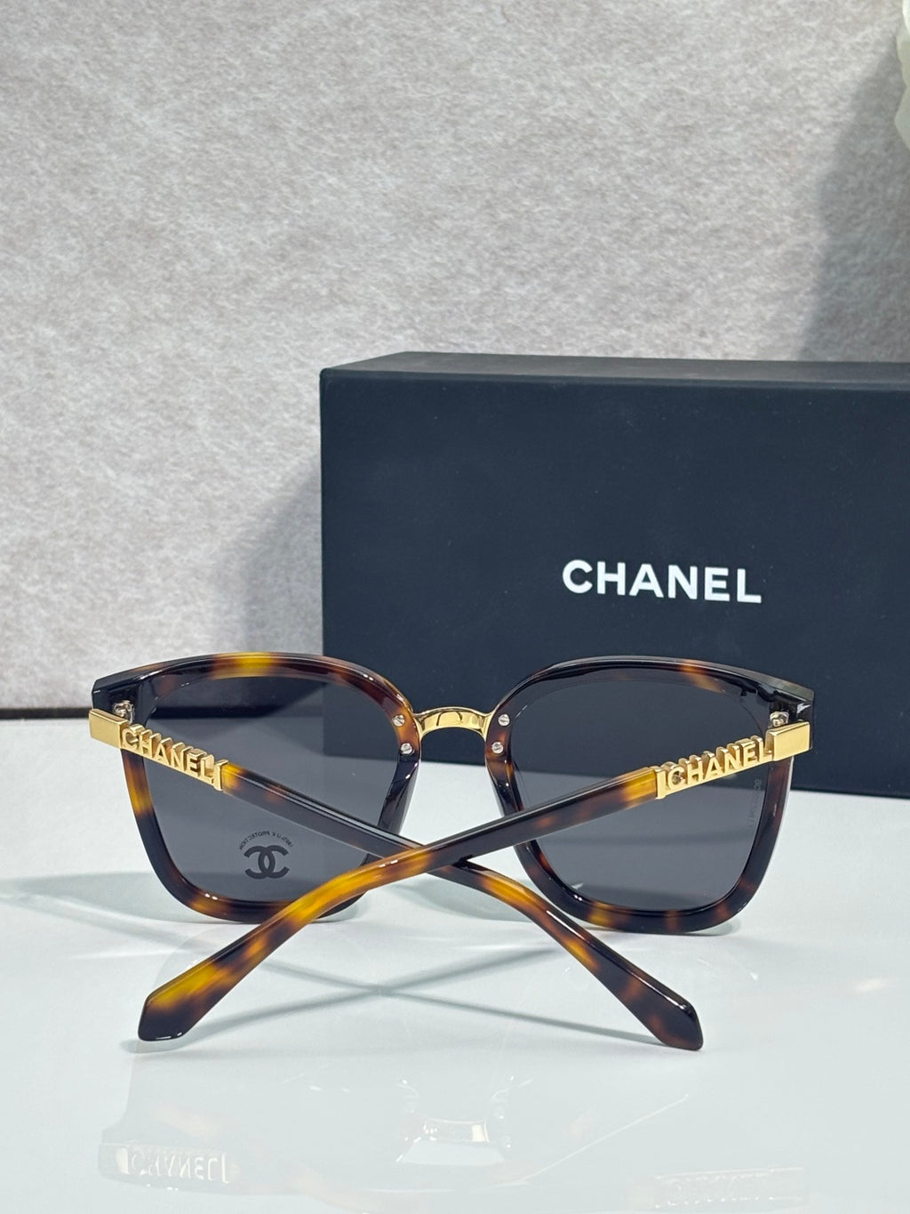 Chanel sunglasses with tortoiseshell frame, dark lenses, and gold logo temple details