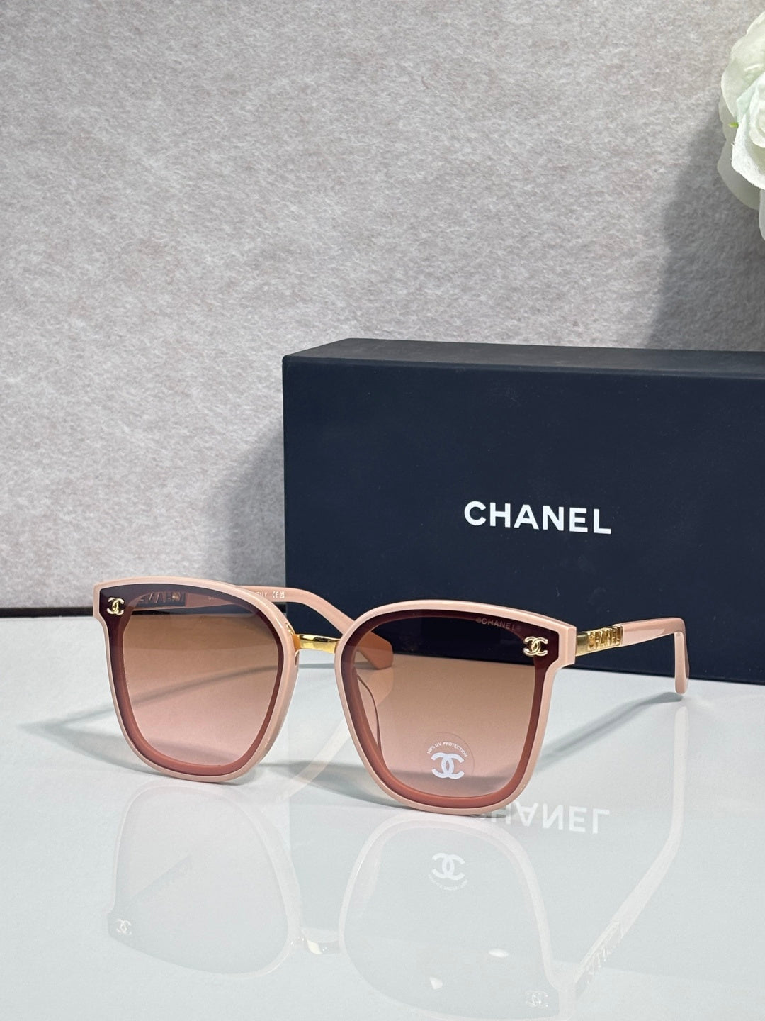 Chanel sunglasses with pink oval frames, dark lenses, and gold logo temple accents