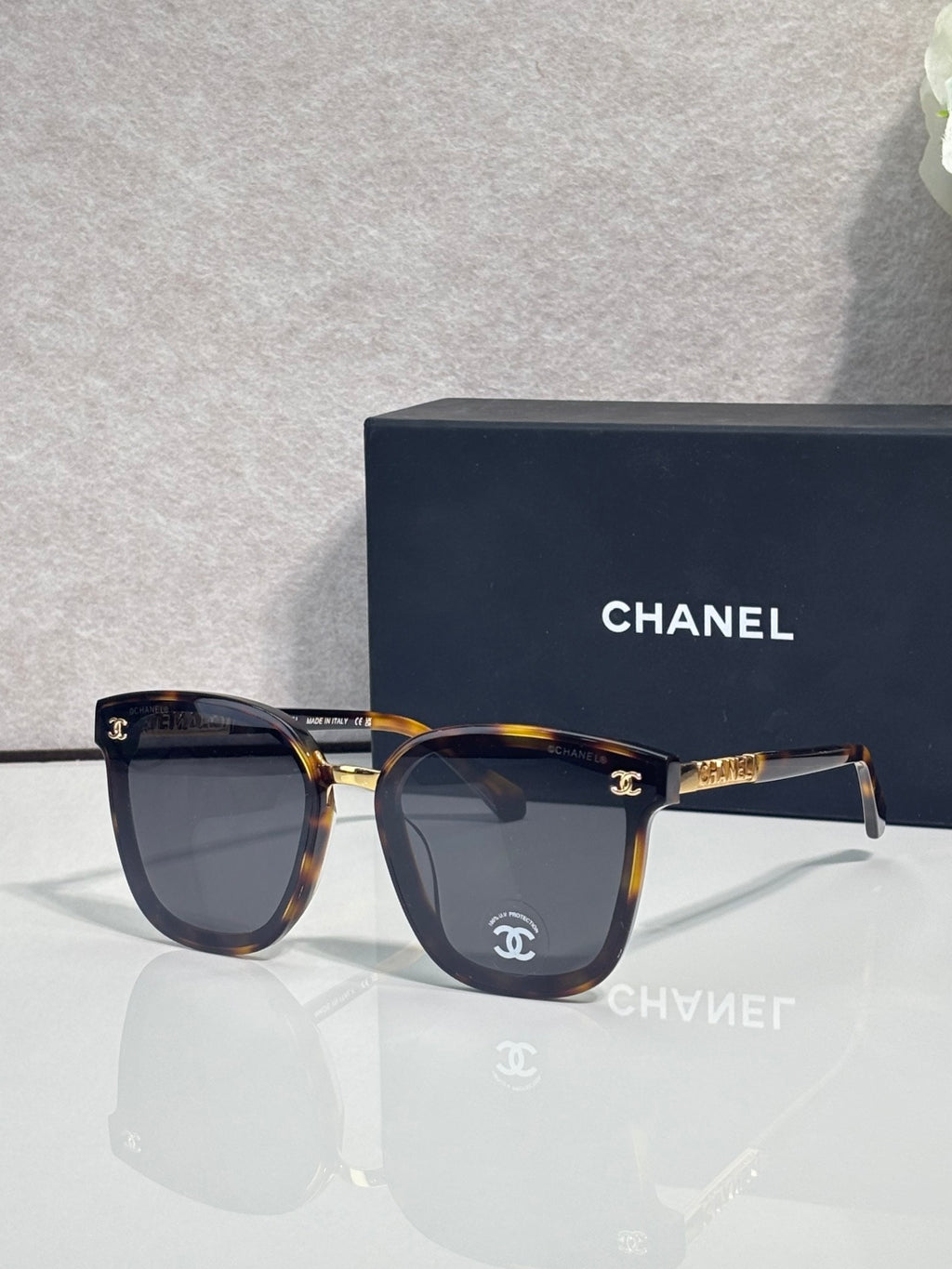 Chanel sunglasses with dark lenses, tortoiseshell frame, and gold logo temple details