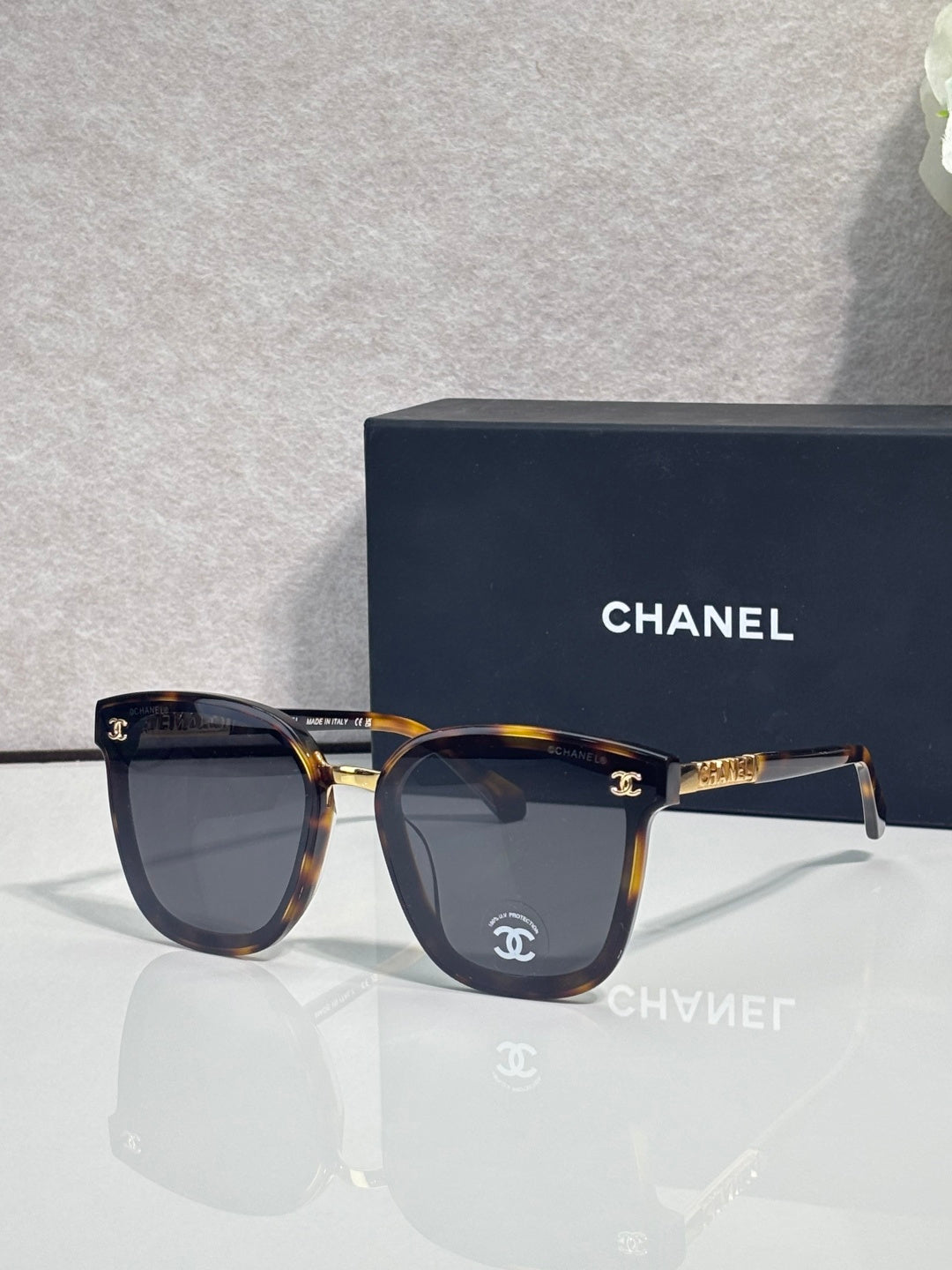Chanel sunglasses with dark lenses, tortoiseshell frame, and gold logo temple details
