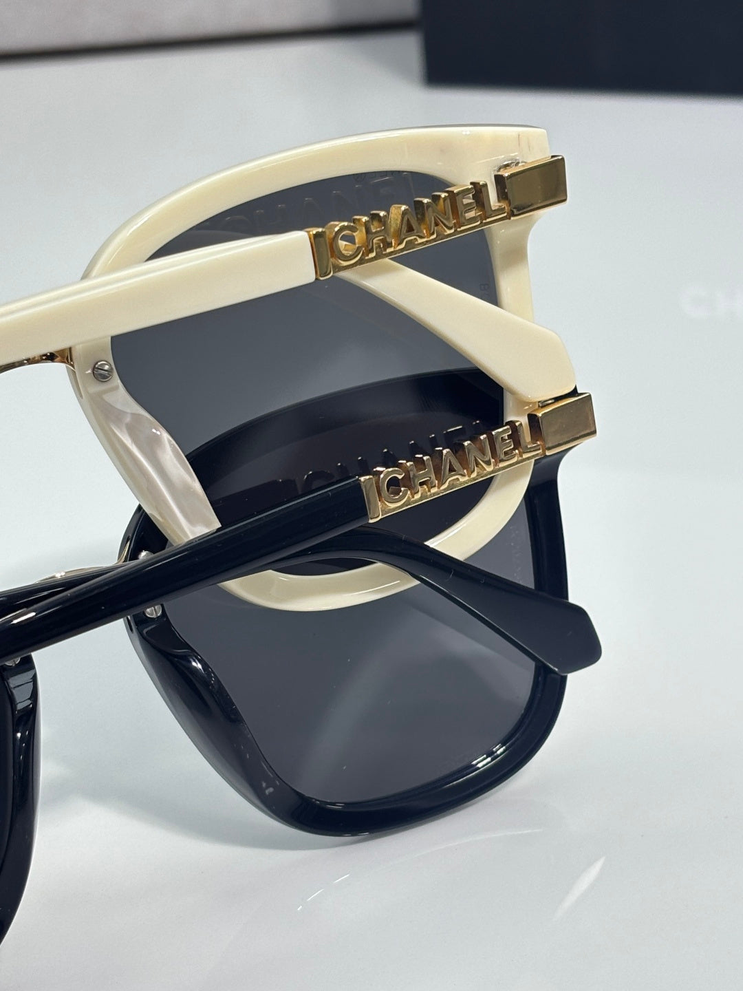 Chanel sunglasses close-up: cream temple with gold CHANEL logo and dark lens