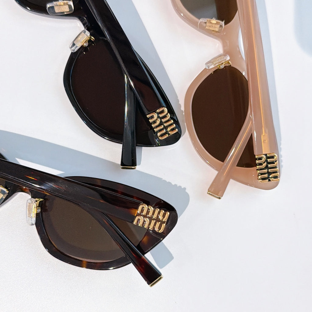 Two cat-eye sunglasses: black and blush-beige frames with dark lenses and gold logos