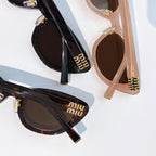 Two cat-eye sunglasses: black and blush-beige frames with dark lenses and gold logos