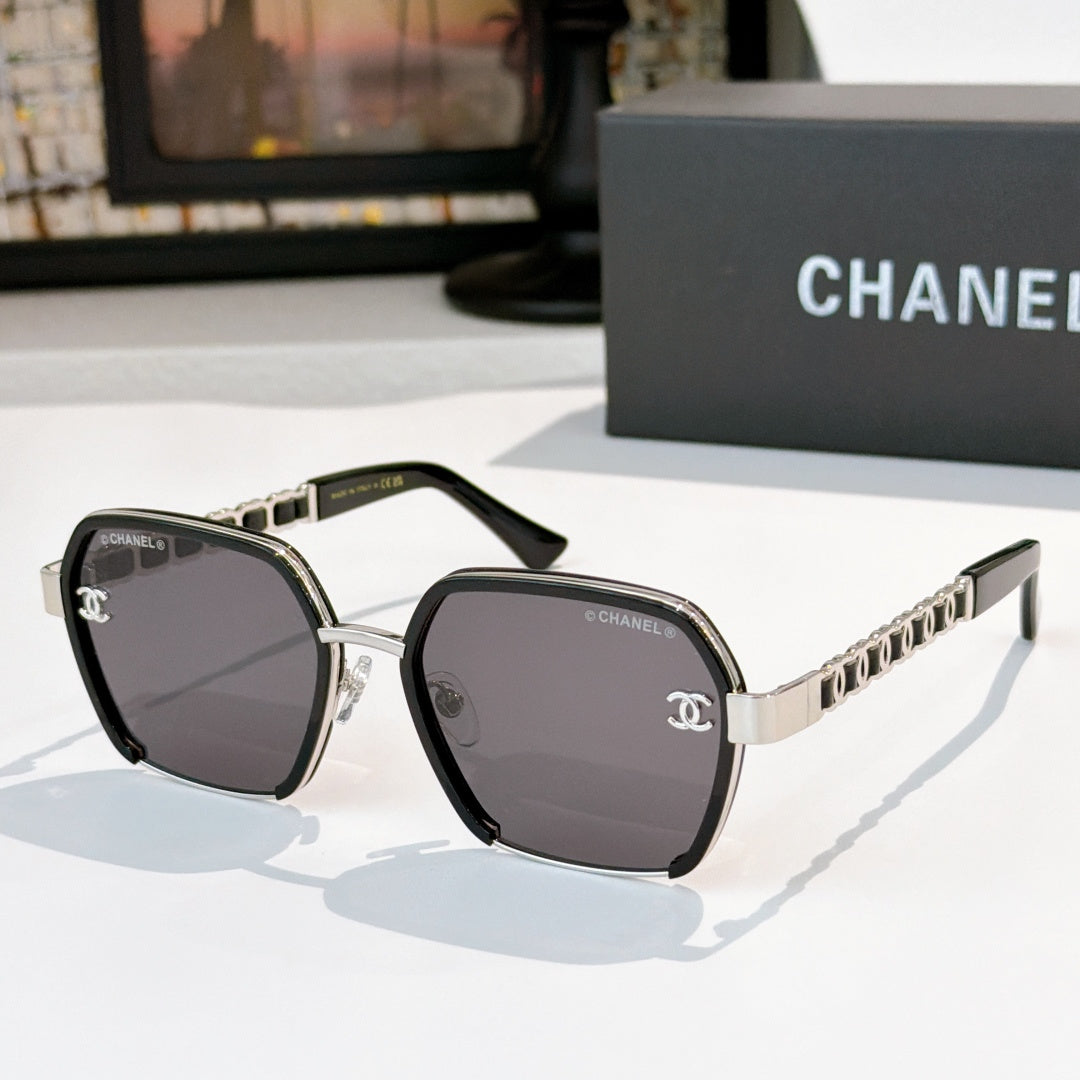 Black sunglasses with dark tinted lenses and gold chain-style temples.
