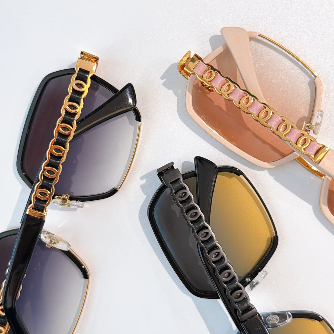 Multiple sunglasses with tinted lenses and chain-style accents on frames.