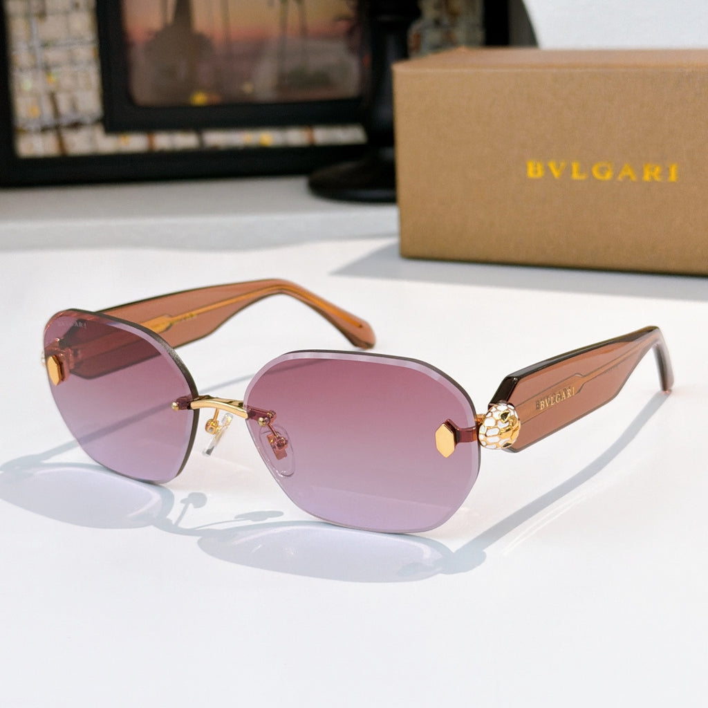 Gold sunglasses with purple-pink lenses and an ornate gold emblem on the temple.