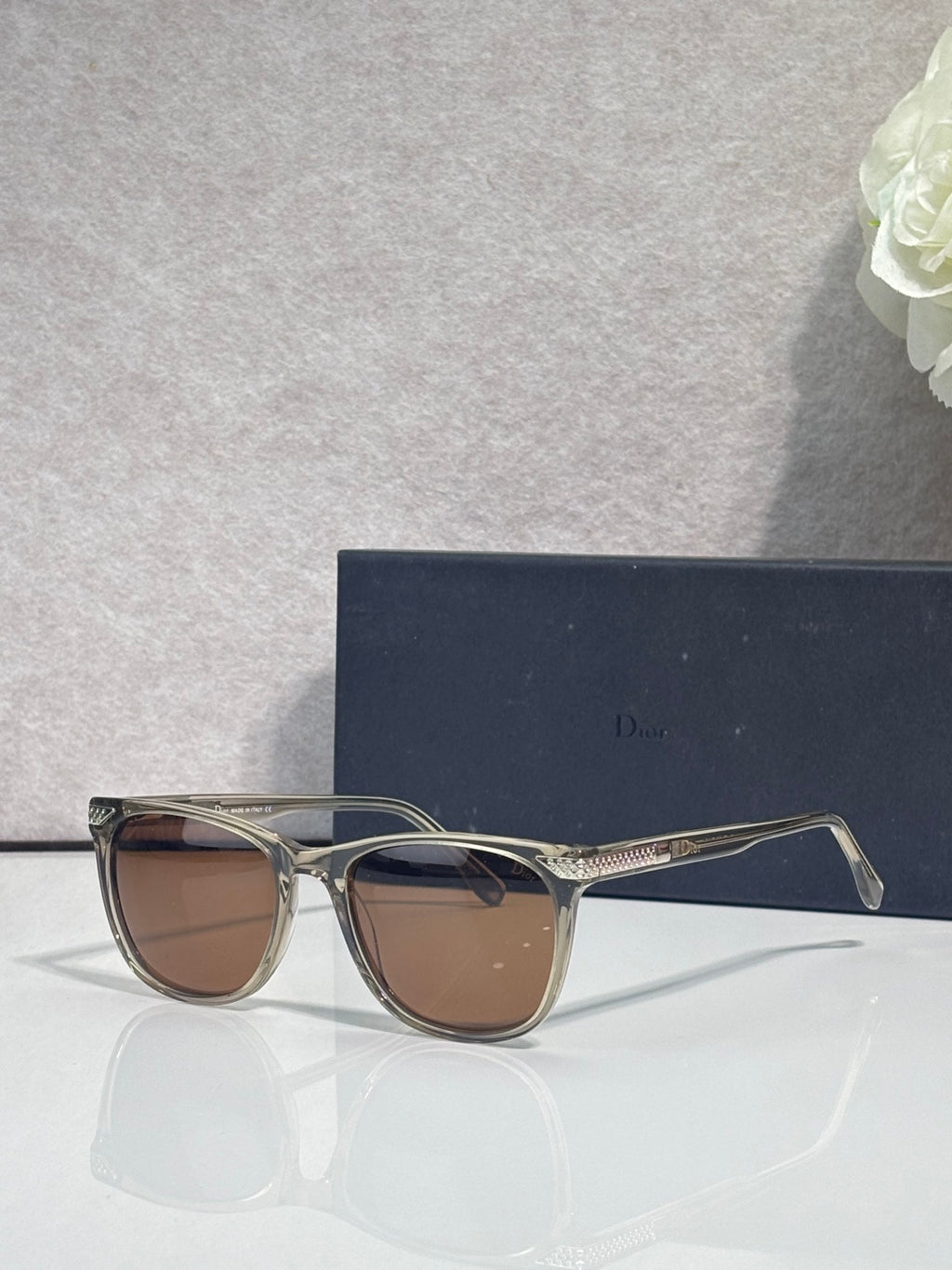 Dior sunglasses with clear frame and brown tinted lenses, side profile view