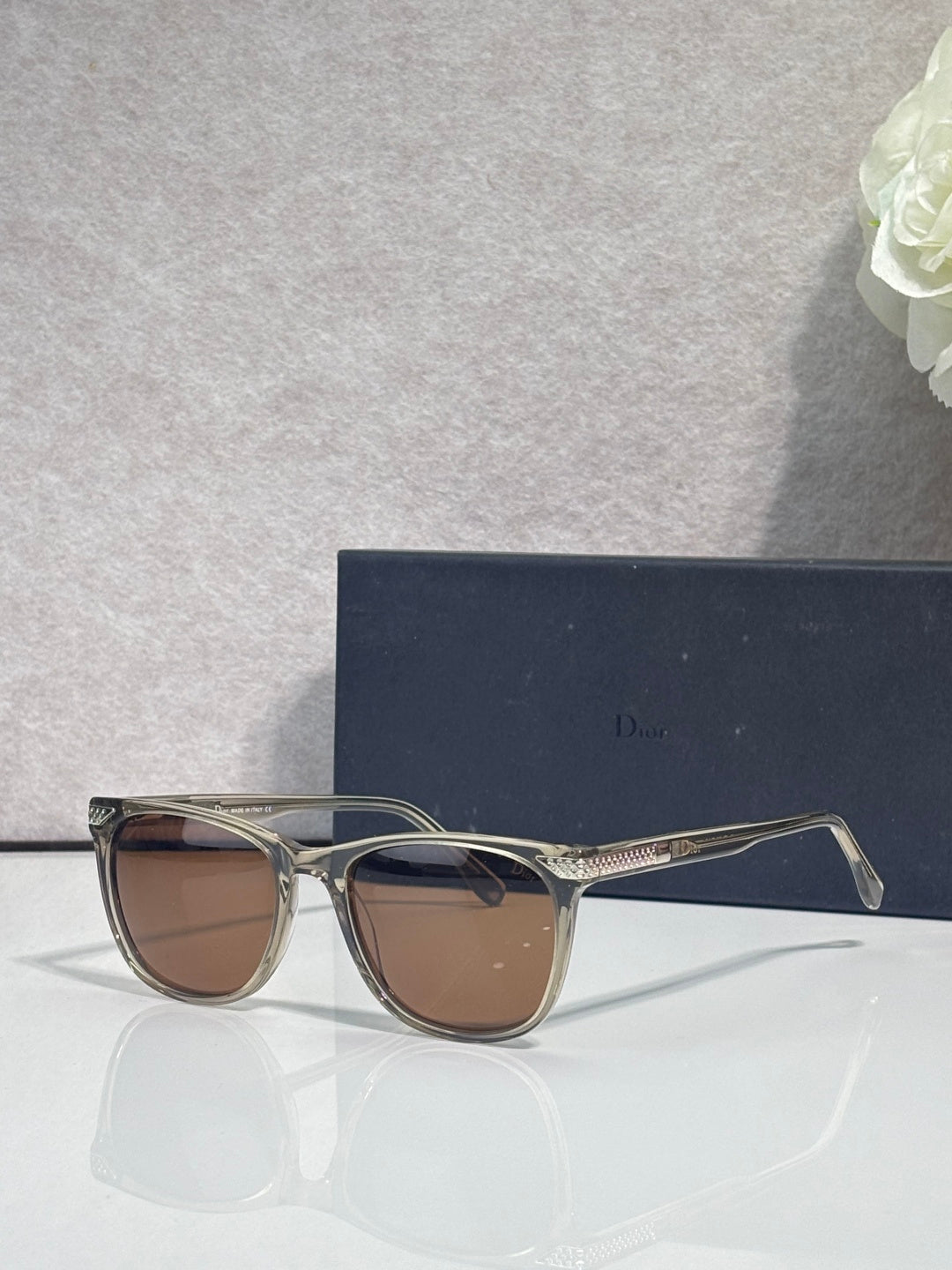Dior sunglasses with clear frame and brown tinted lenses, side profile view