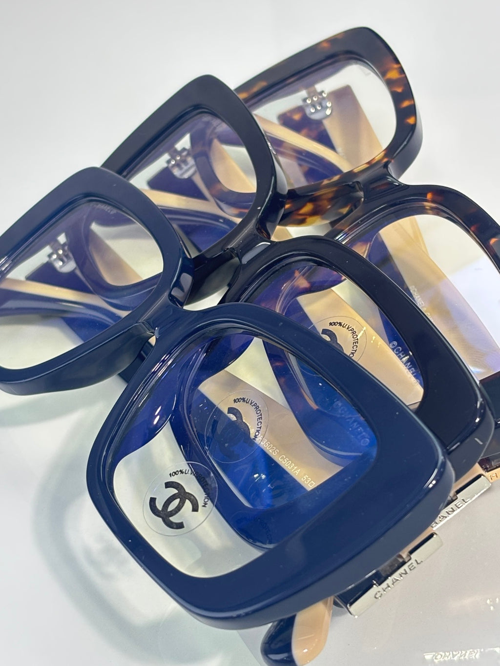 Chanel glasses close-up: blue square frames with clear lenses and gold logo