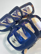 Chanel glasses close-up: blue square frames with clear lenses and gold logo