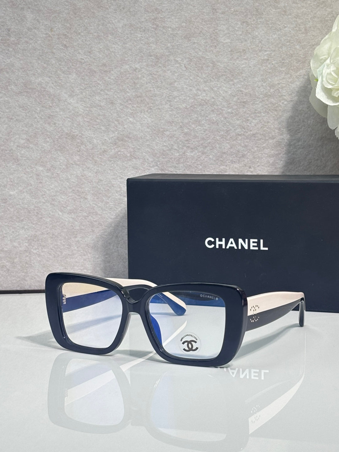 Chanel glasses with dark blue square frames and clear lenses, gold-tone arms