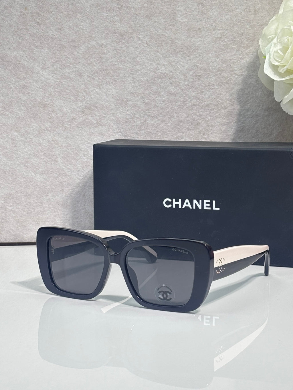 Chanel glasses with dark blue frames and gray-lensed square lenses, side logo on temples