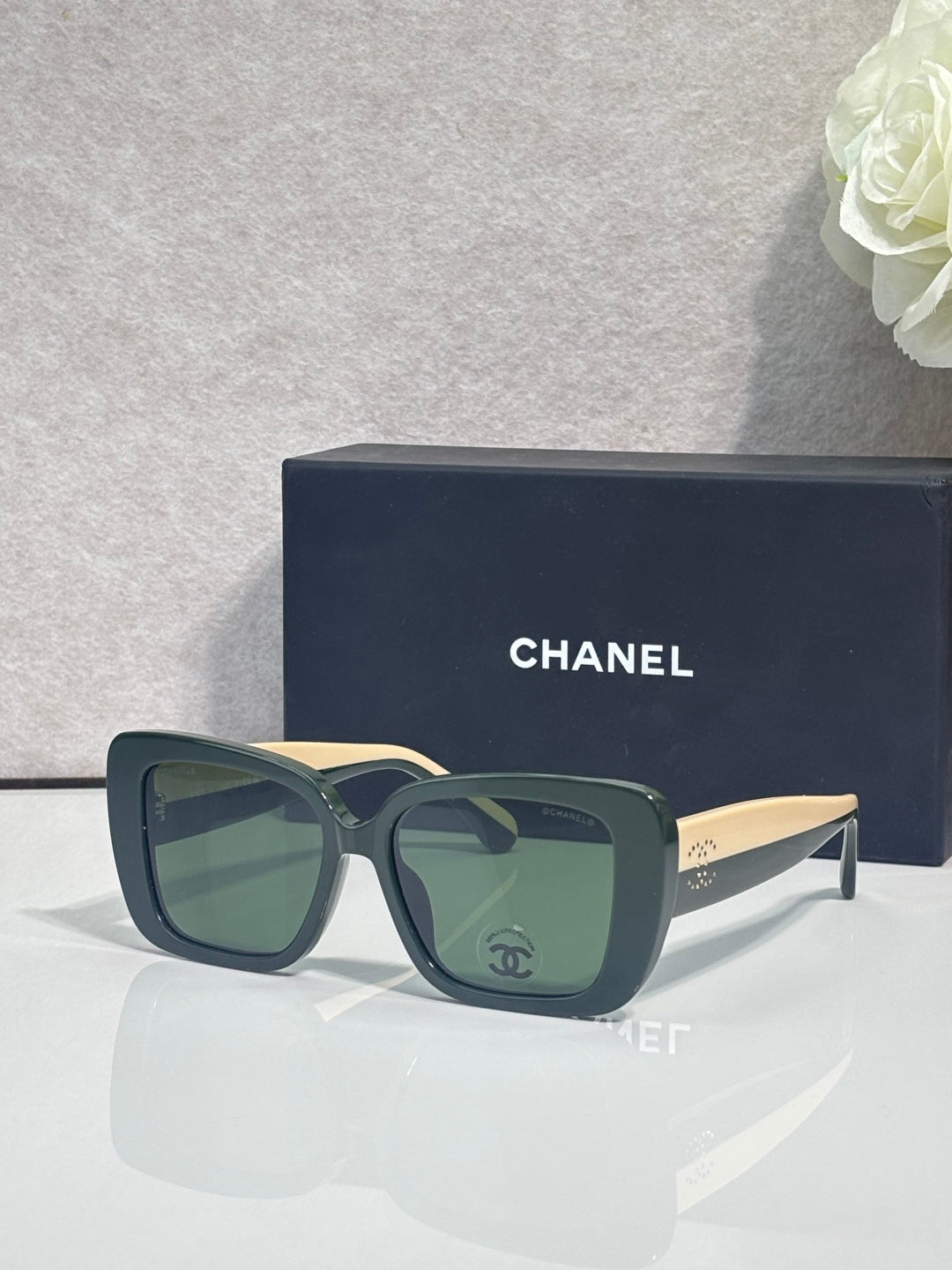Chanel glasses with dark blue frames and green-tinted lenses, gold-tone temple tips