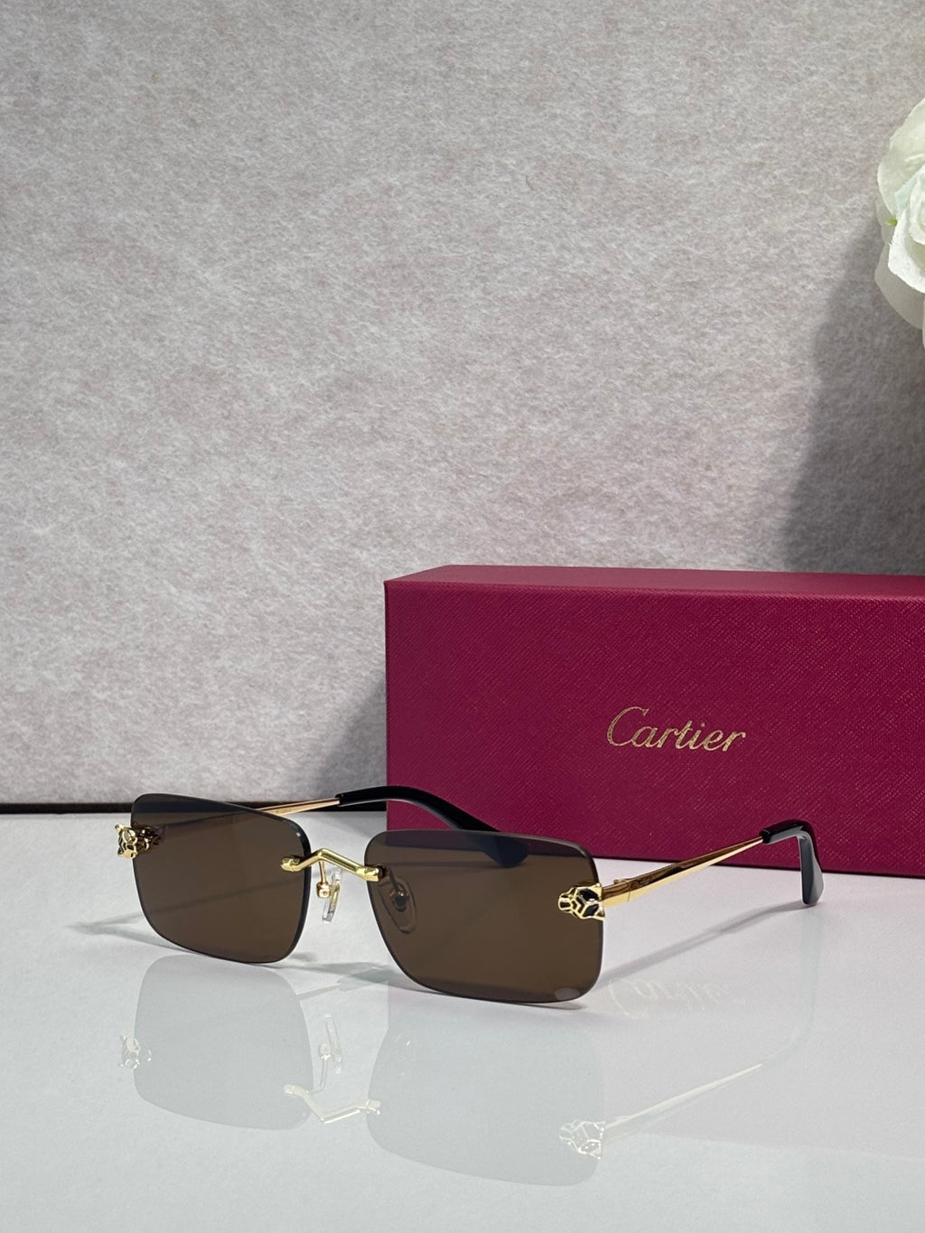 Rectangular eyeglasses with gold frame, dark brown lenses, and black temple arms