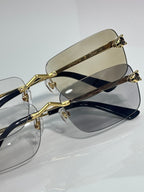 Gold-rim eyeglasses with clear lenses and dark blue temples, geometric hinge details