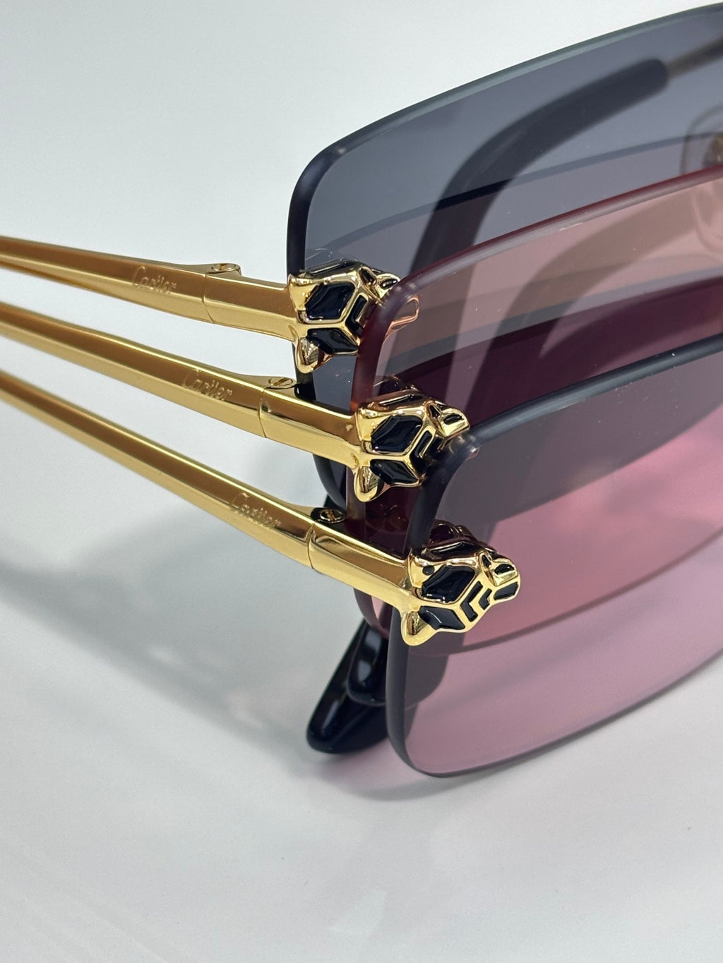 Close-up of gold eyeglass frame with pink tinted lenses and geometric hinge details