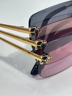Close-up of gold eyeglass frame with pink tinted lenses and geometric hinge details