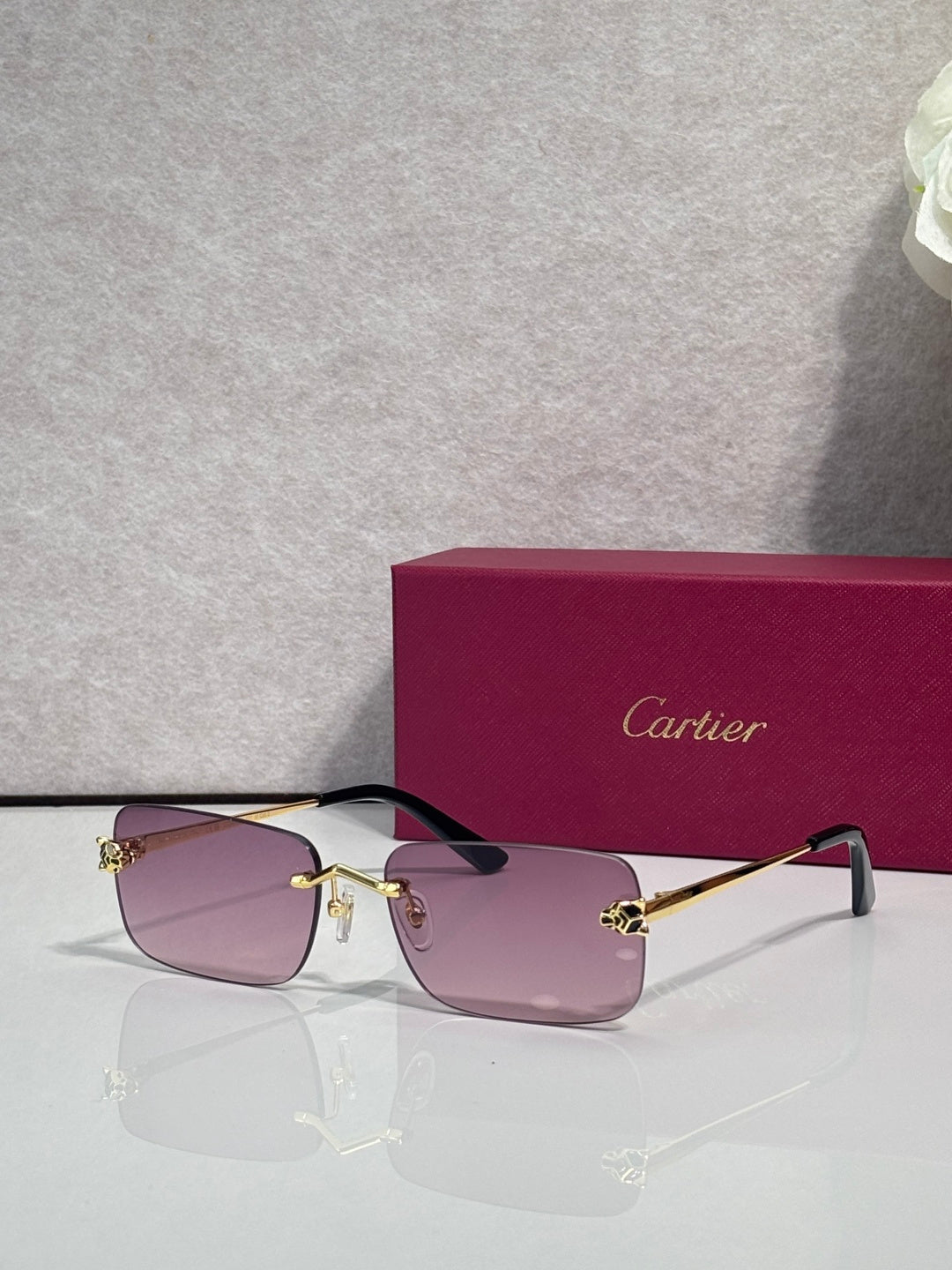 Rectangular eyeglasses with gold frame and light pink tinted lenses, black temple arms