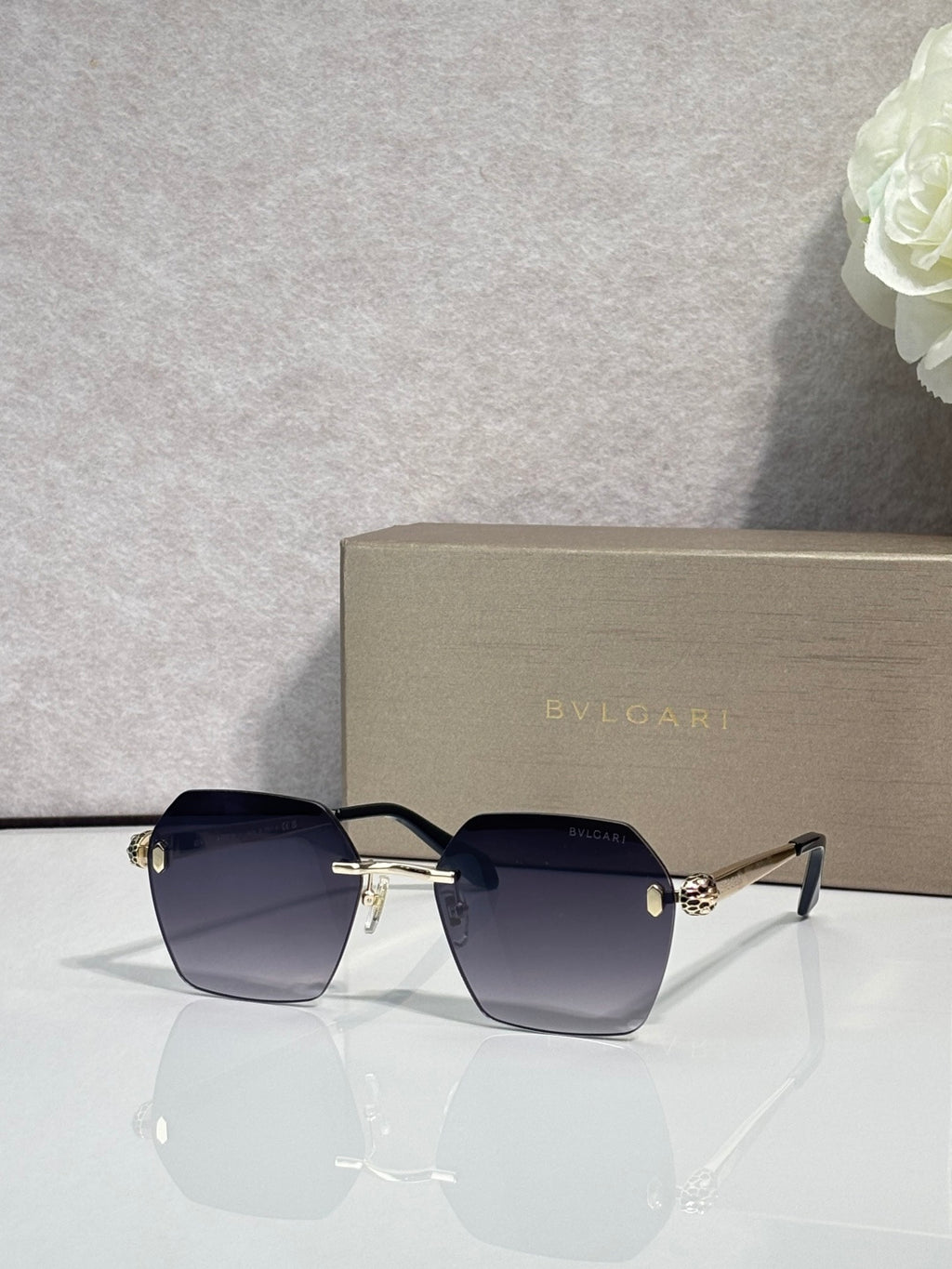 Rectangular dark navy sunglasses with black frame and gold emblem bridge