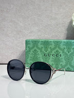 Round sunglasses with dark lenses; gold-tone frame and black outer rims.