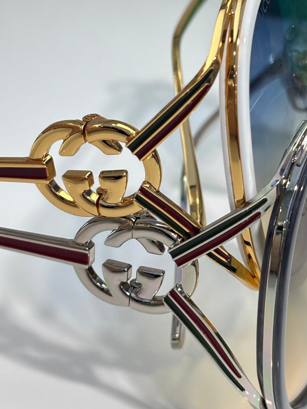 Gold-tone sunglasses detail with emblem on the temple and round lens edge.