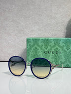 Round sunglasses with dark lenses; blue outer rims and gold-tone temples.
