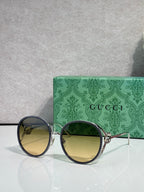 Round sunglasses with dark lenses; gold-tone frame and black outer rims.