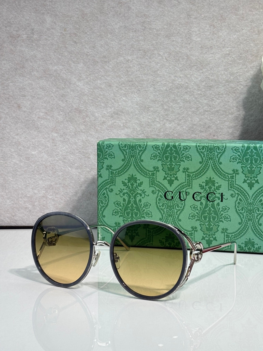 Round sunglasses with dark lenses; gold-tone frame and black outer rims.