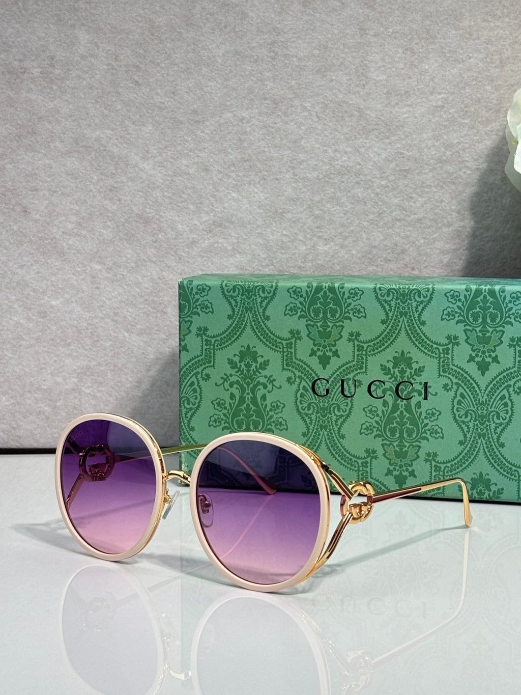 Round sunglasses with purple-tinted lenses; gold-tone frame and purple outer rims.