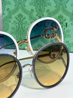 Close-up of round sunglasses; gold-tone and blue-tone frames with tinted lenses.