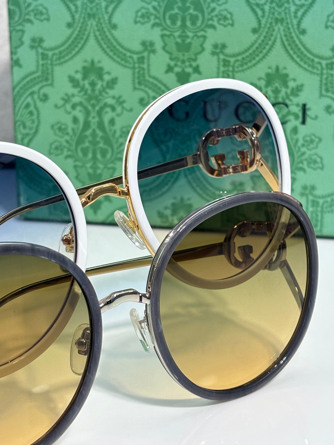 Close-up of round sunglasses; gold-tone and blue-tone frames with tinted lenses.